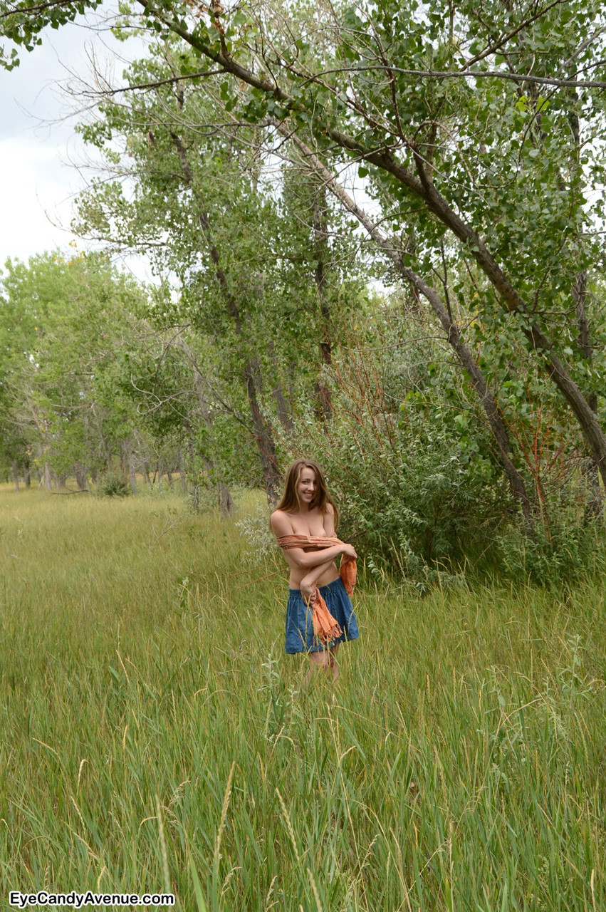 Nice teen Jamie models naked amid long grasses in a country setting